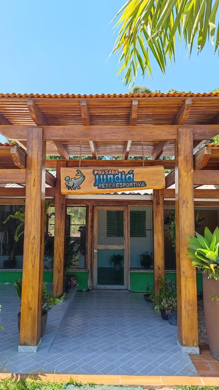 Entrance of Pousada Jundiá with its wooden sign and palm trees